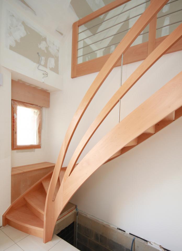 escalier tournant contemporain avec noyaux évidés sur mesure en france. escalier à contre-marche, garde-corps en bois + inox