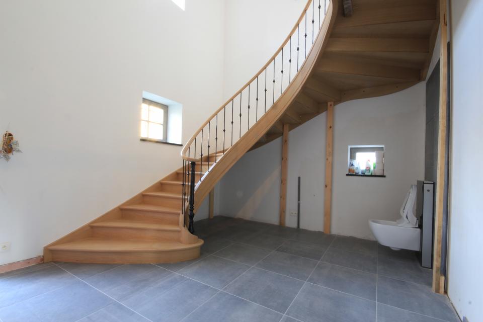 escalier balancé classique avec limons cintrés (lamellé collé) en bois sur mesure. escalier à contres-marches, colonnes et fuseaux en acier, peints en noir.
