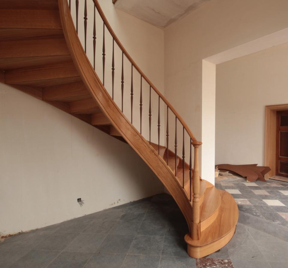 escalier balancé classique avec limons cintrés (lamellé collé) en bois sur mesure. escalier à contre-marche, colonnes et fuseaux tournées en bois.